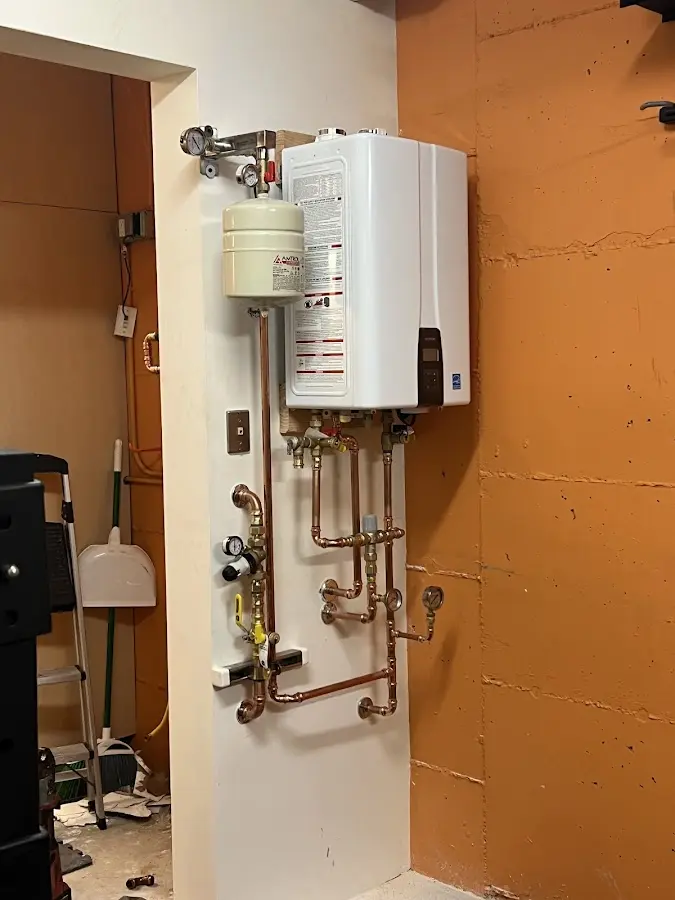 Plumbing technician inspecting water heater connections in Spencerport